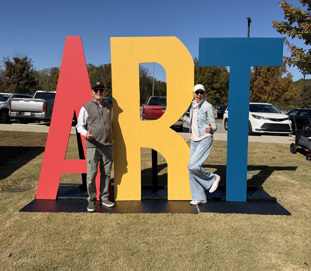 Two Etowah Arts supporters posing with the colorful ART sign