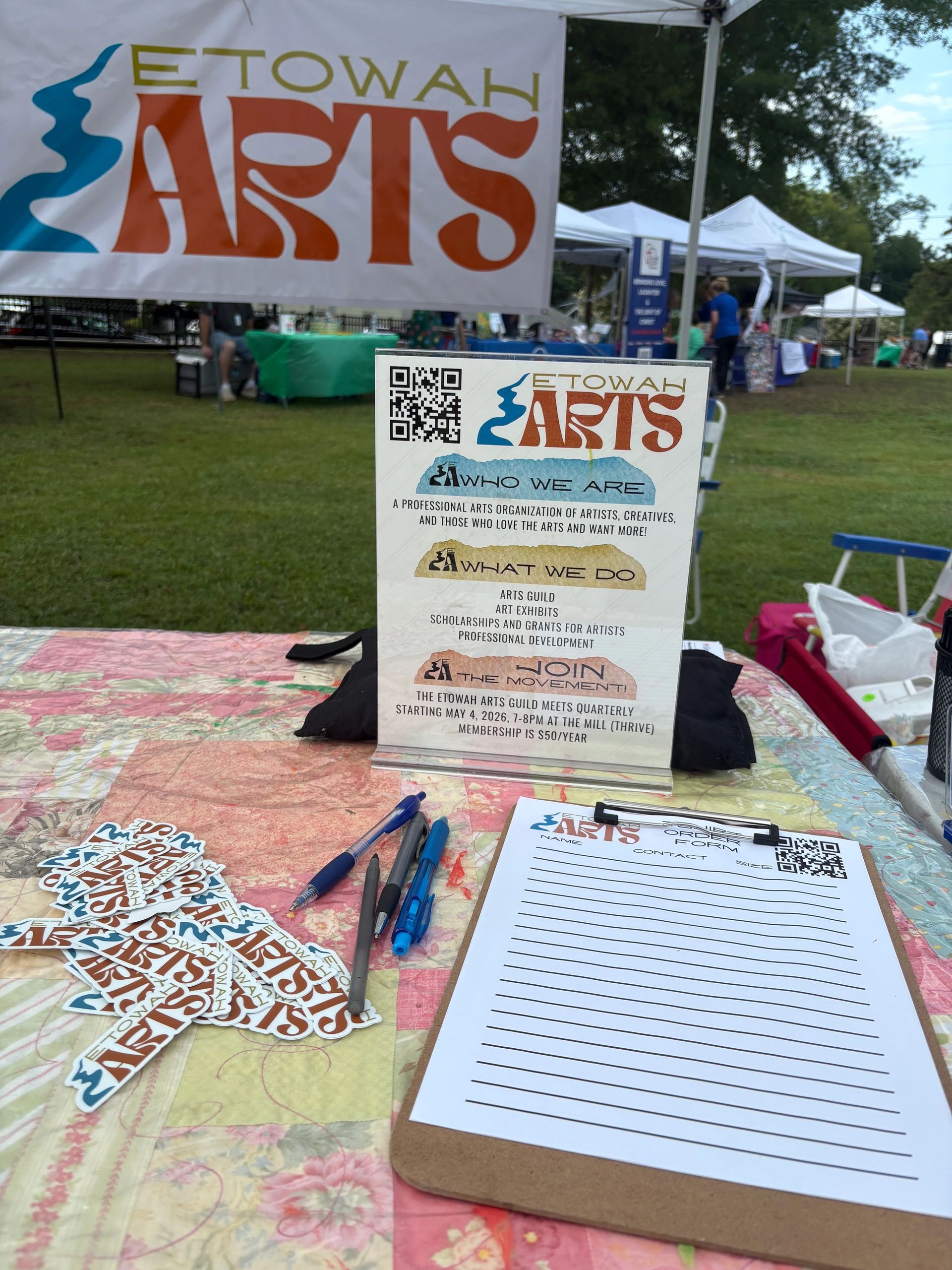 Etowah Arts information booth with sign-up sheet at an outdoor festival
