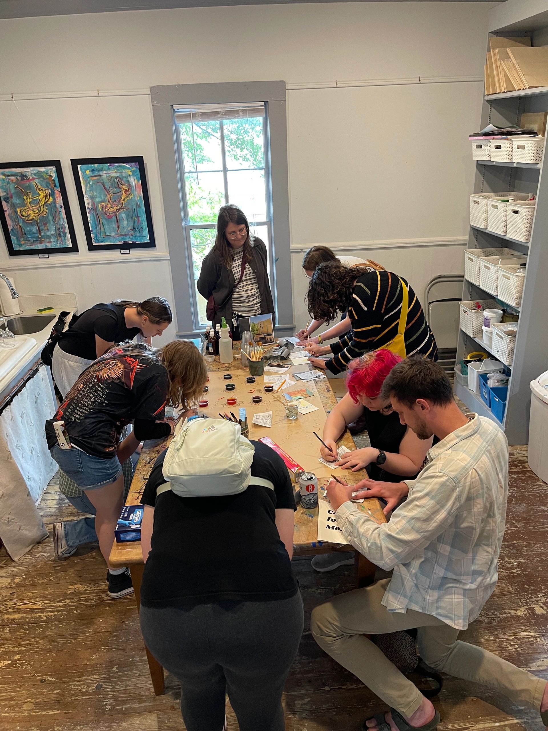 Students and artists working together around a studio table