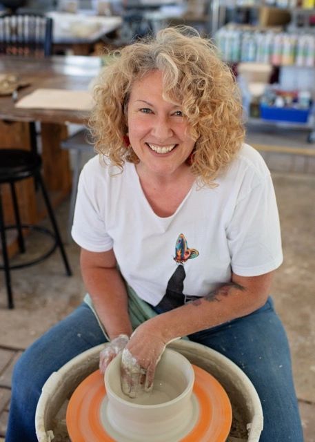 Shanna Coulter smiling at a pottery wheel