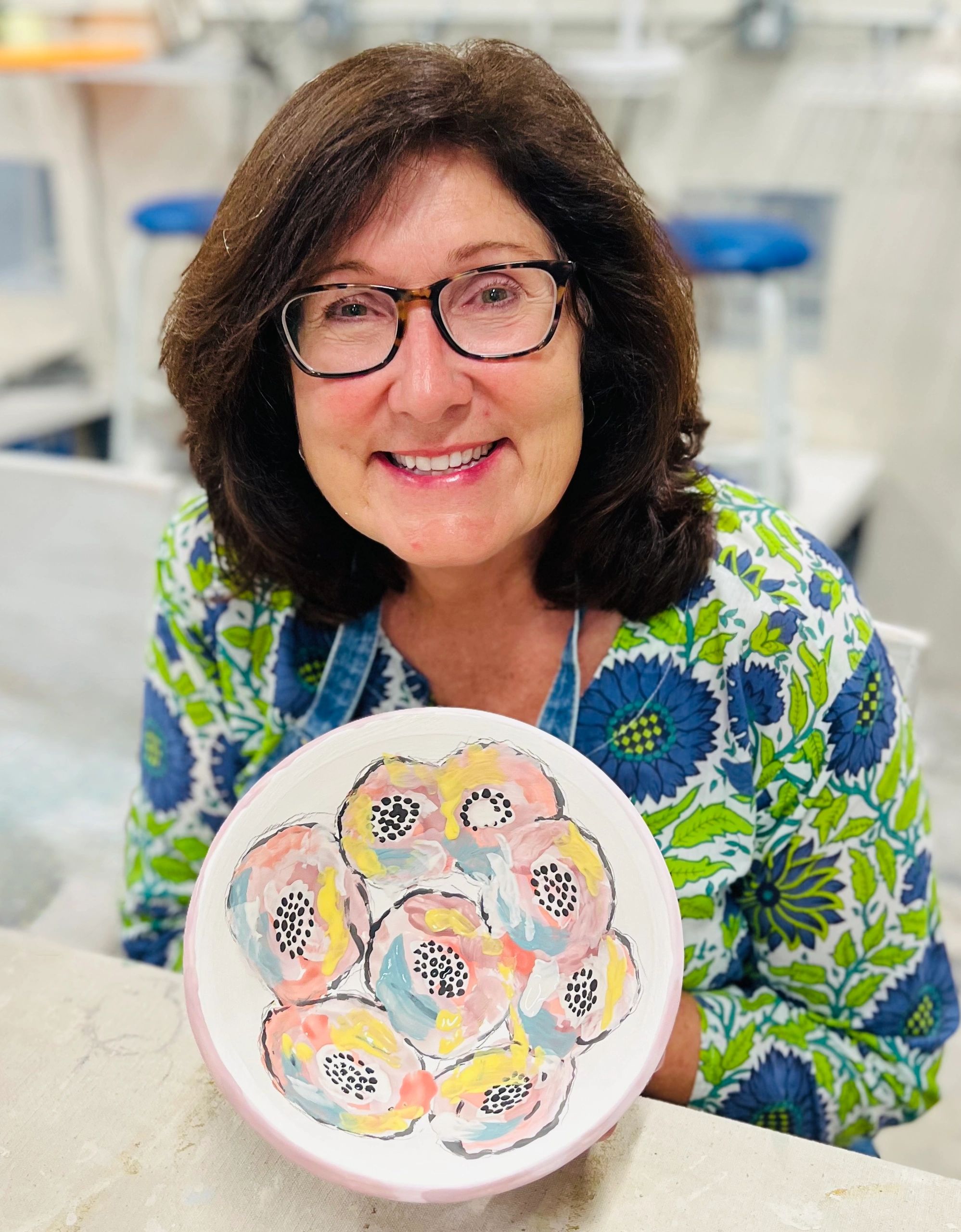 Maria Farrar holding a hand-painted ceramic plate