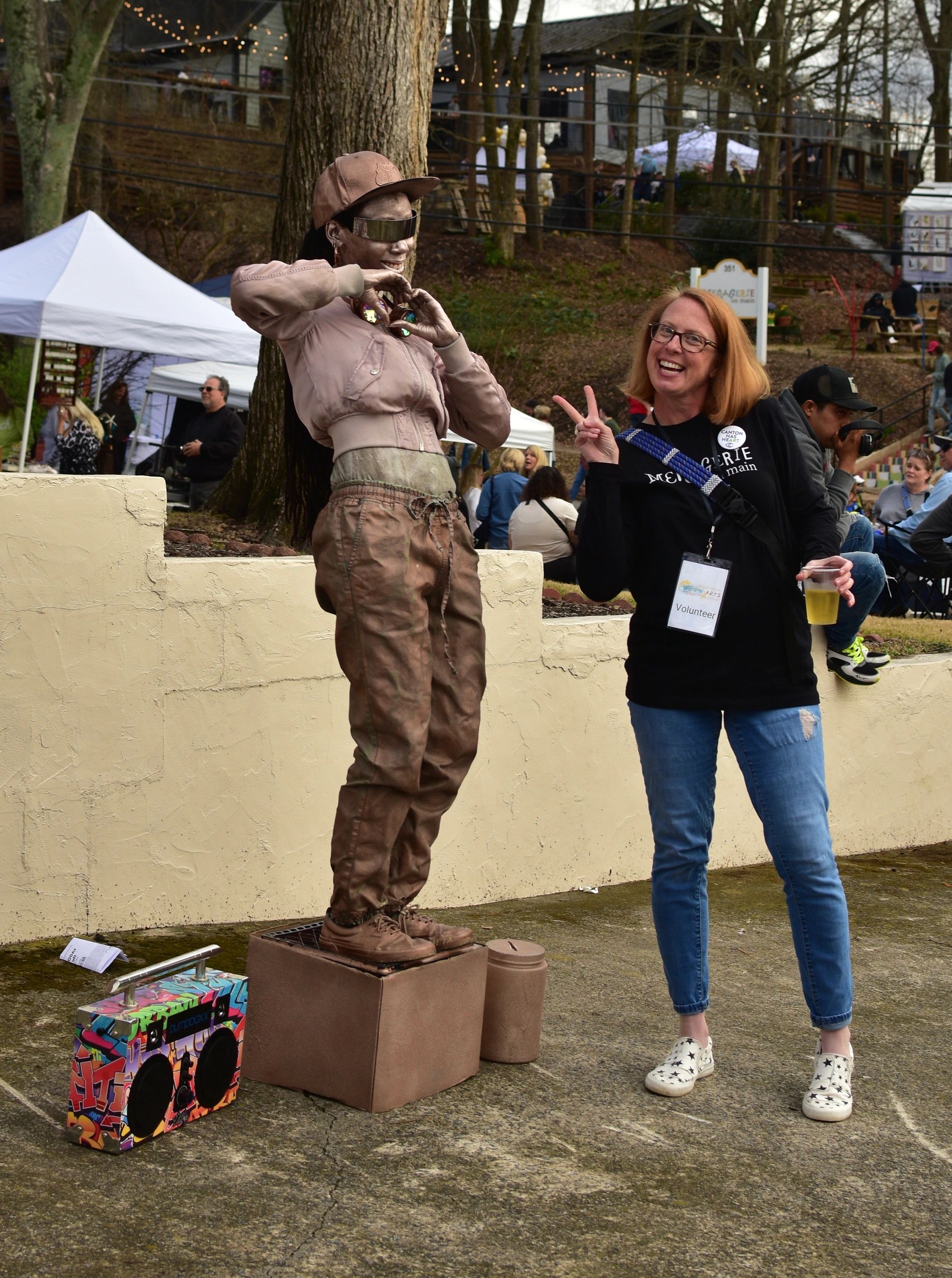 Artist posing with a life-size sculpture at an outdoor arts festival